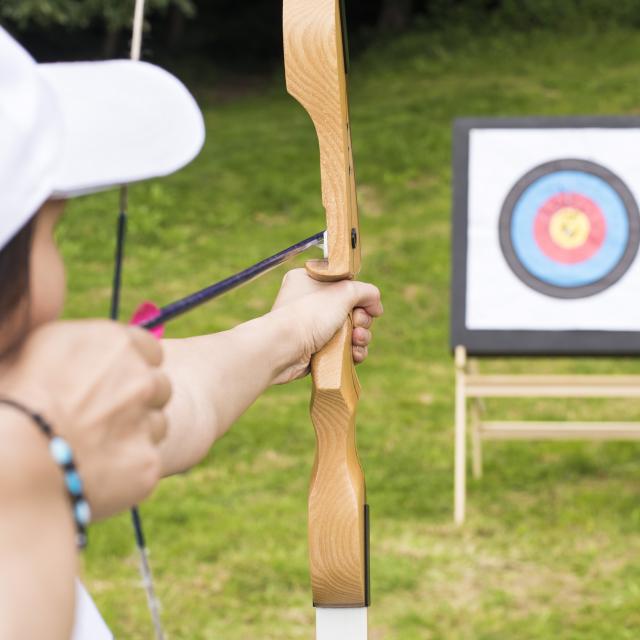 A young female archer holding his bow aiming at a target - sport and recreation concept